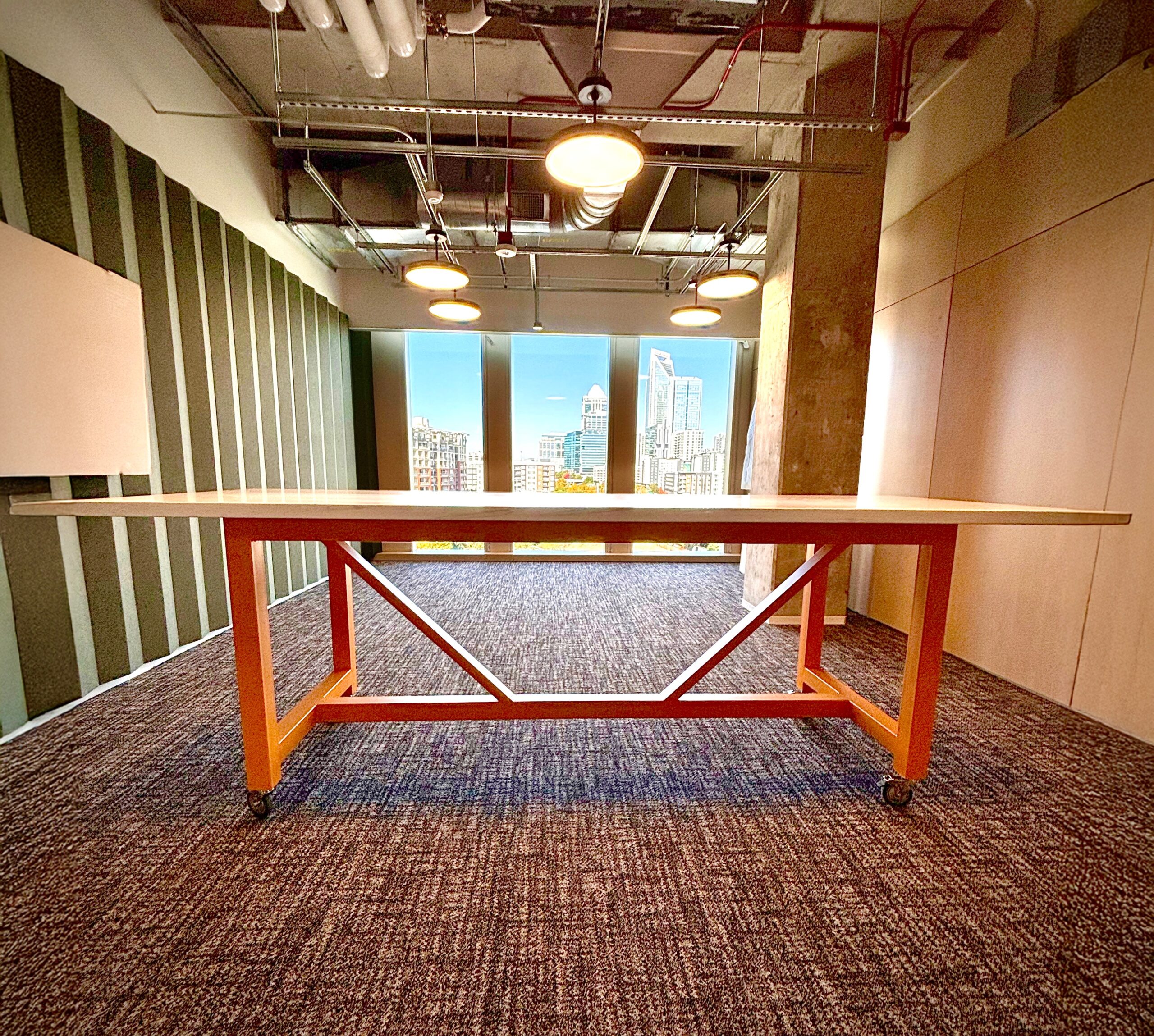Wormy maple community table with painted steel base on casters